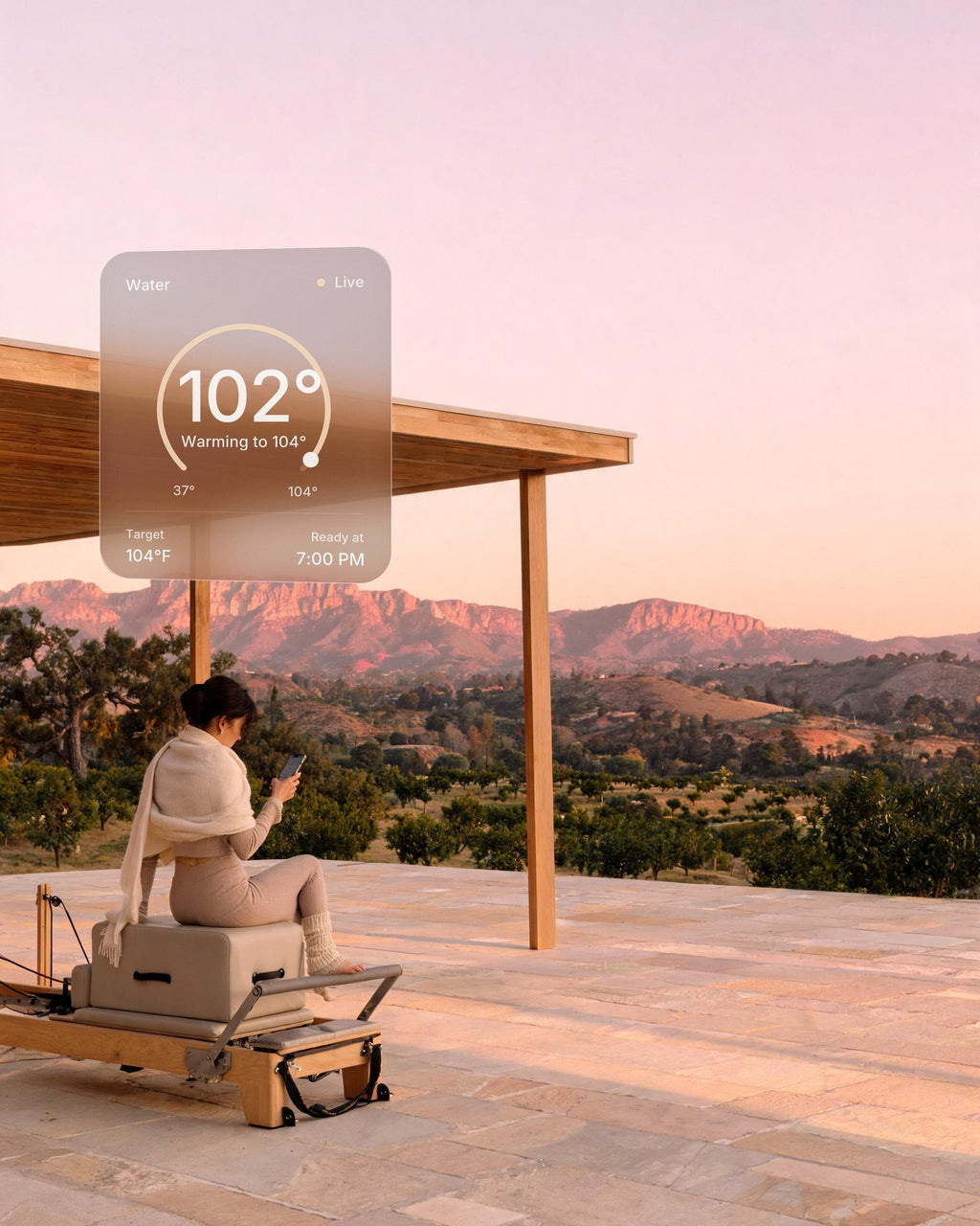 A woman after a Pilates session in an open pavilion at sunset warms her hot and cold vessel at home from her phone: 102°F, ready at 7:00 PM