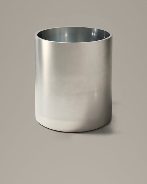 Brushed stainless steel cylindrical bathing vessel on a warm grey studio backdrop