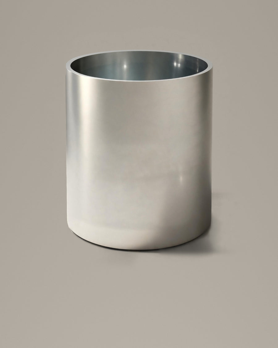 Brushed stainless steel cylindrical bathing vessel on a warm grey studio backdrop