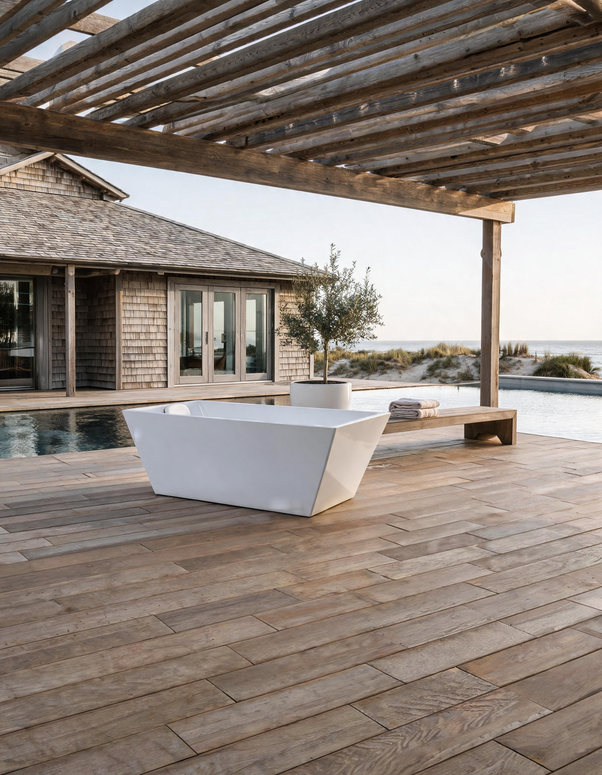 TIDE vessel on a timber deck under a pergola beside a pool, a shingled house and the sea beyond
