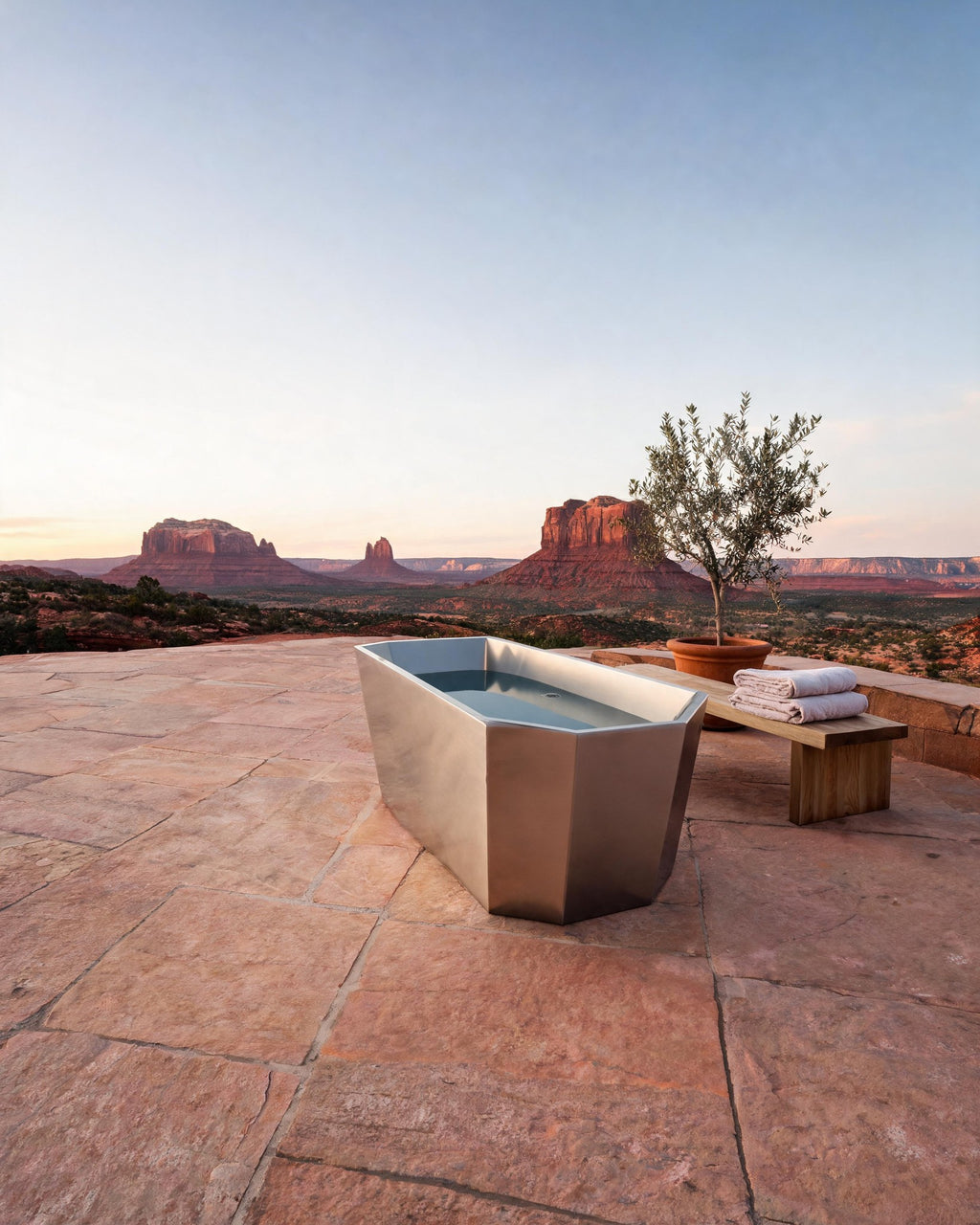 FACET octagonal vessel in Satin Steel with cold water on a red sandstone terrace at dawn, desert buttes beyond
