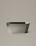 FACET octagonal vessel in Satin Steel, side view, on a warm grey studio background