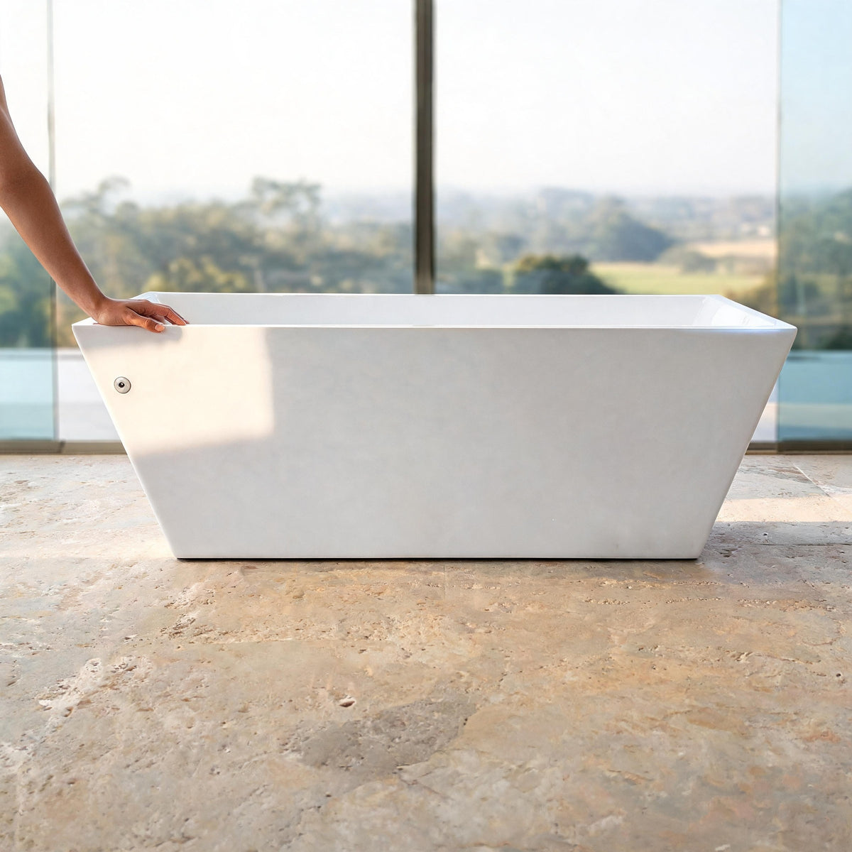 TIDE vessel in white acrylic in daylight on a travertine floor, a hand resting on its rim