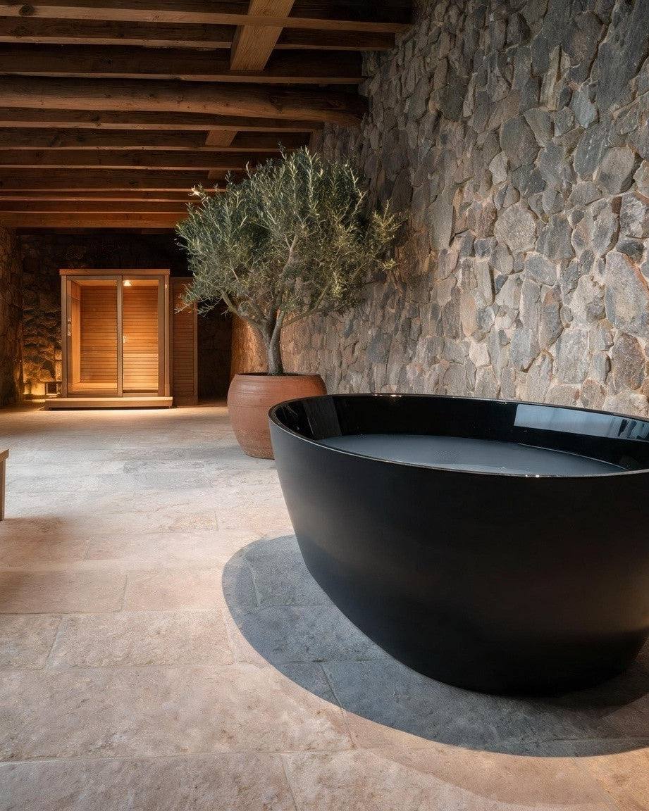 OVUM vessel in black acrylic in a stone room with tall windows onto a misty forest, an oak bench beside it