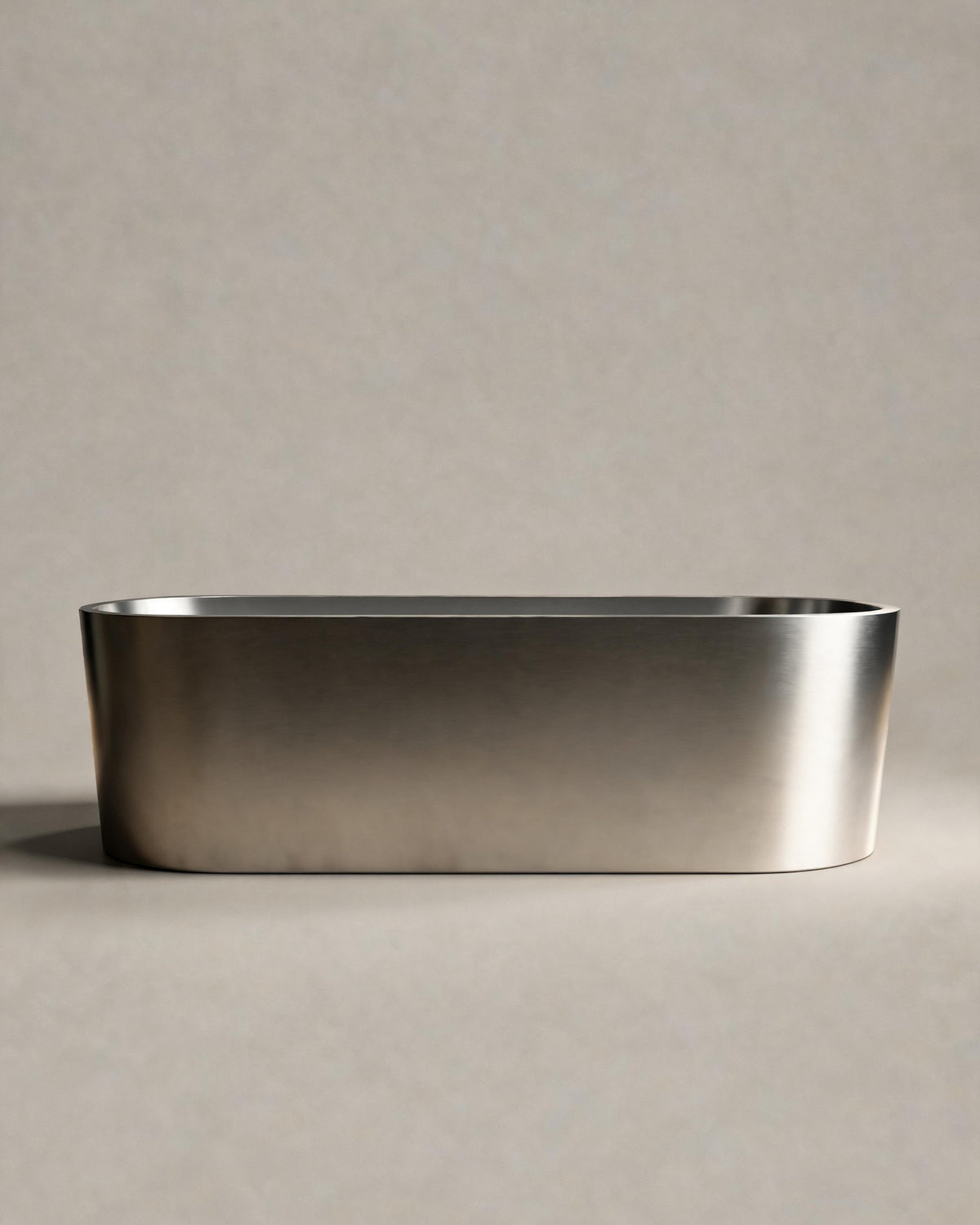 OBLONG hot and cold vessel, a long oval in Satin Steel, side view on a warm grey studio background
