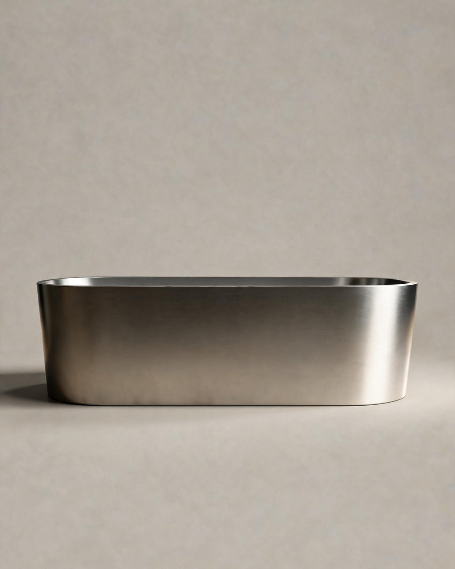 OBLONG hot and cold vessel, a long oval in Satin Steel, side view on a warm grey studio background