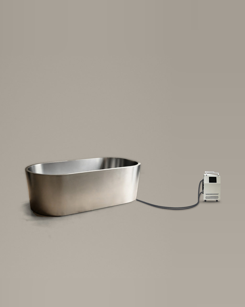 Brushed stainless steel oval bathing vessel on a warm grey studio backdrop beside its Hot & Cold Unit, connected by two braided hoses