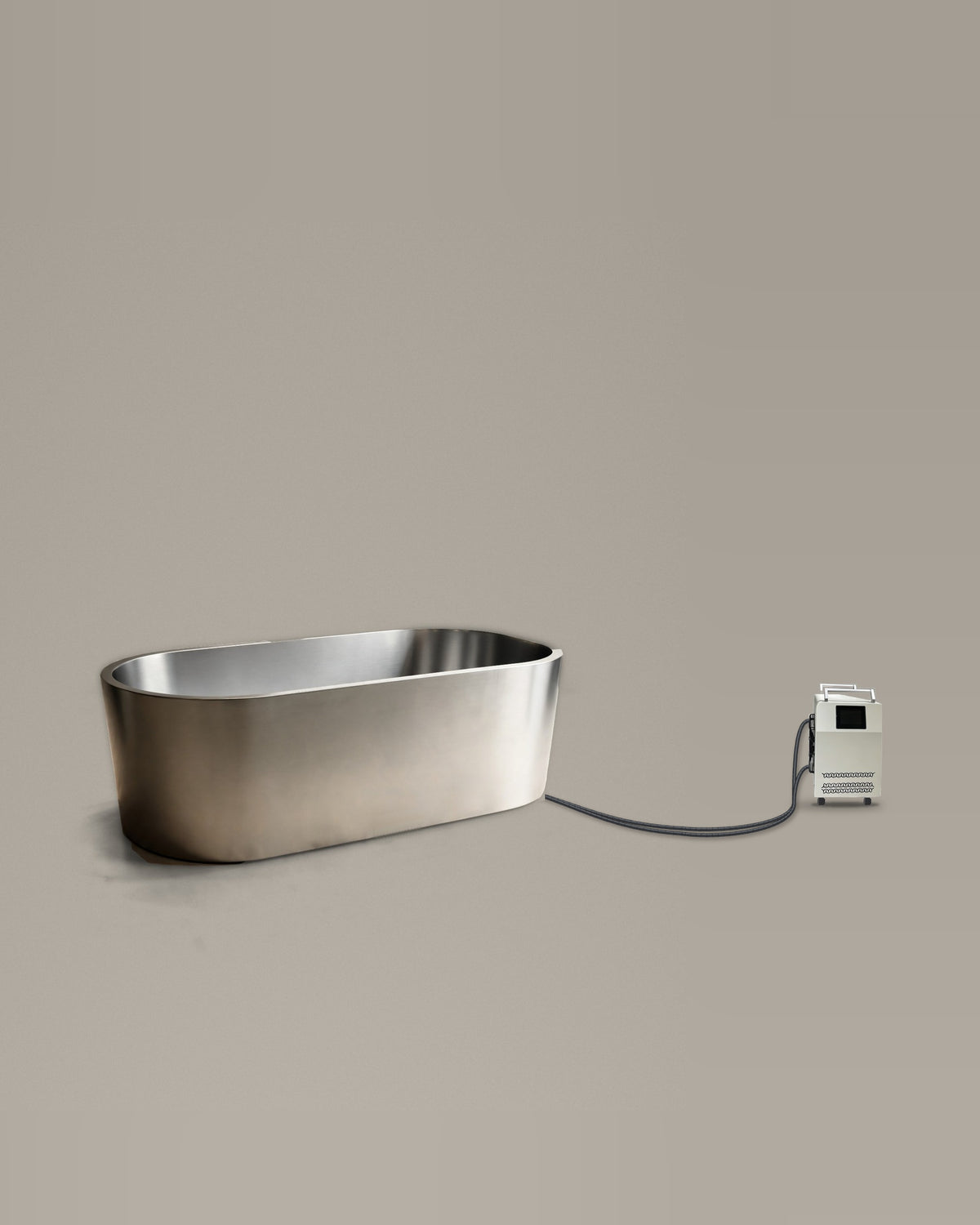 Brushed stainless steel oval bathing vessel on a warm grey studio backdrop beside its Hot & Cold Unit, connected by two braided hoses