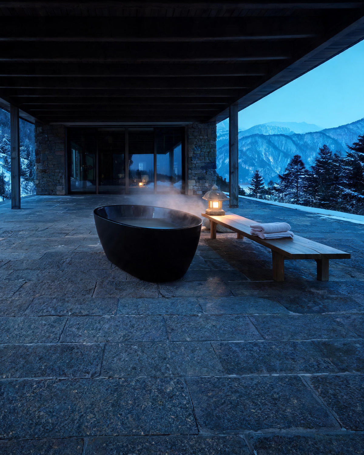 OVUM vessel in black acrylic set warm under a stone loggia facing snowy mountains at blue hour, steam rising, a lantern glowing