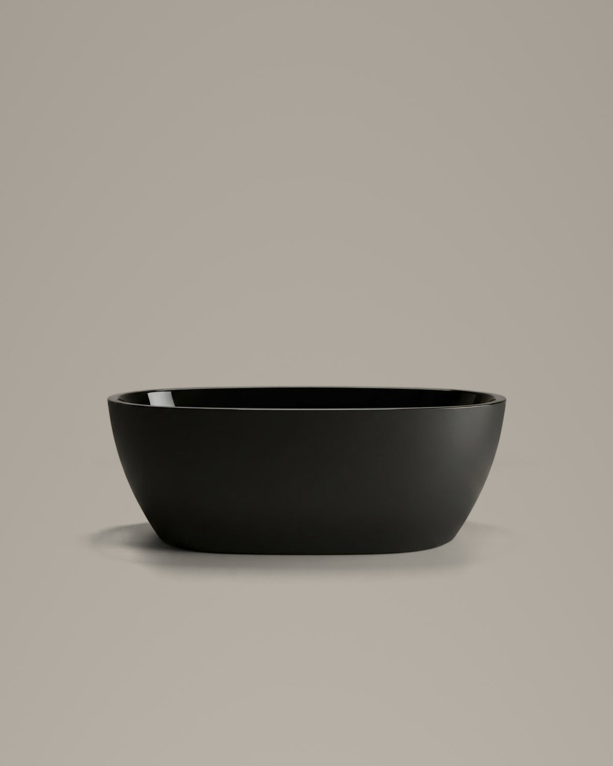 OVUM black egg-shaped vessel, side view, on a warm grey studio background