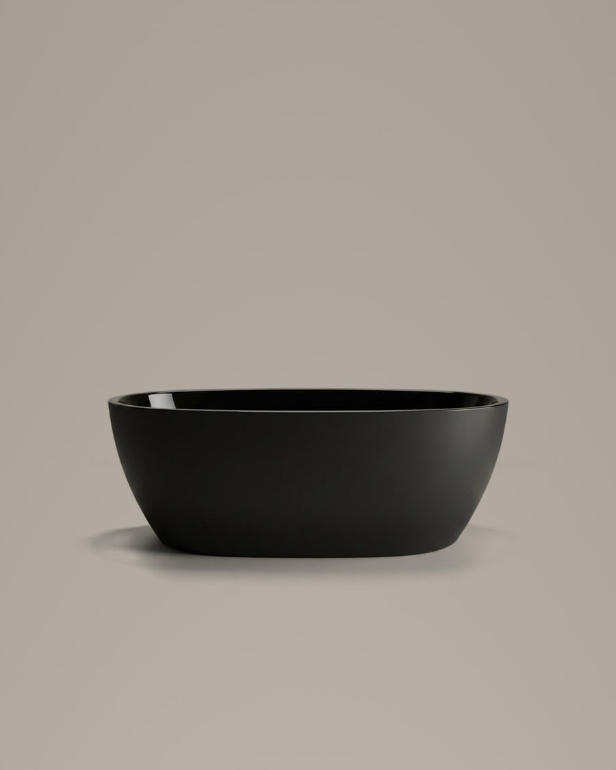 OVUM black egg-shaped vessel, side view, on a warm grey studio background
